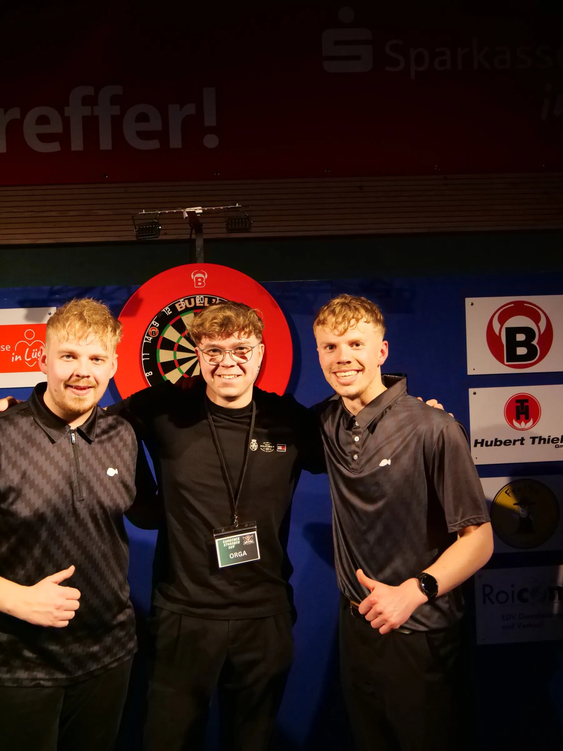Drei Spieler vor der Dartscheibe